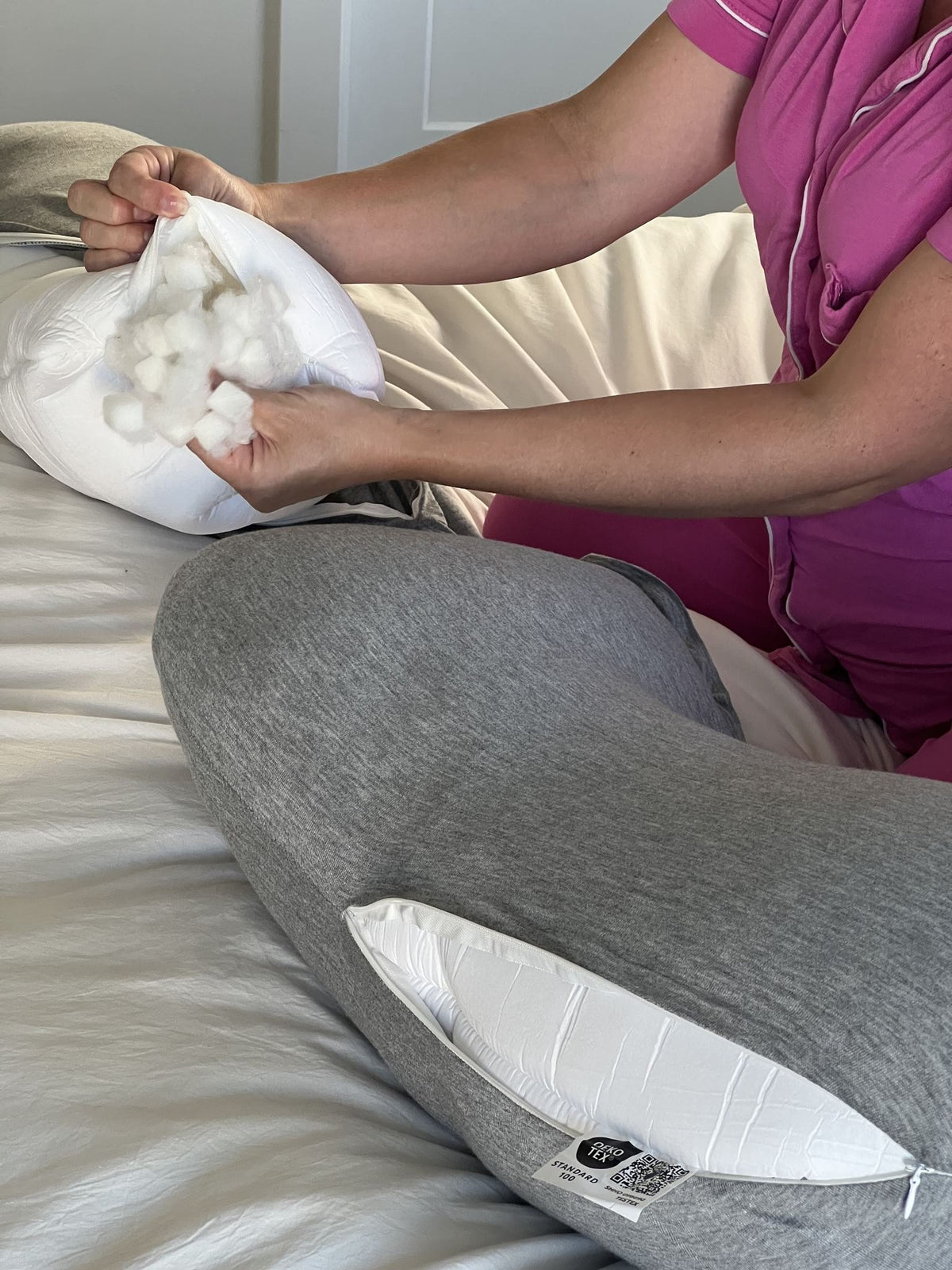 Hands adding fill to Araluna's inner pillow through its zipper